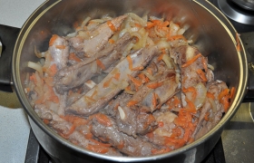 Перекладываем ребрышки с луком и морковью в посуду для  тушения . Мясо на ребрышках уже практически готово.