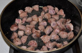 В просторной тяжелой сковороде сначала  перекаливаем масло  – и только тогда выкладываем мясо, которое, помешивая, обжариваем 2-3 минуты до образования корочек.  