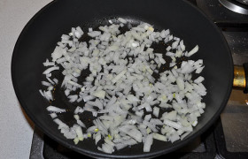 Тем временем очищаем и шинкуем мелко луковицу, засыпаем в сковороду с сильно разогретым маслом. Пассеруем (обжариваем) при помешивании, пока лук станет золотистым и почти мягким – 5-7 минут.
