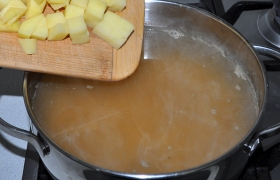 В суп, где варится горох, кладем нарезанный кубиком картофель, бросаем лавровый лист, горошки перца. Оставляем вариться под крышкой, снизив огонь.