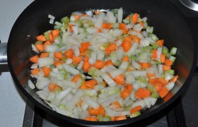 Снижаем под сковородой огонь до среднего, всыпаем лук, сельдерей, морковь.  Пассеруем  6-7 минут. 