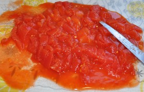 Вскрываем баночку томатов, выкладываем в тарелку, измельчаем.