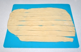 Часть теста раскатываем в лепешку (4-5 мм толщины) и нарезаем полоски примерно той же ширины, что и яблочные дольки, или чуть меньше.