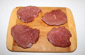 Делим говядину на 4 отбивные по 20-22 мм толщины (поперек волокон мяса). И несильными ударами молотка  отбиваем  обе стороны, делая их тоньше почти вдвое. Обязательно кончиком ножа рассекаем имеющиеся жилки, чтобы они не «стянули» мясо во время жарки. 
 
 
 
