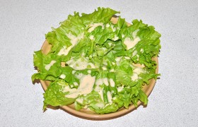Зеленые салатные листья рвем руками и выкладываем на салатницу. Поливаем примерно третью соуса.