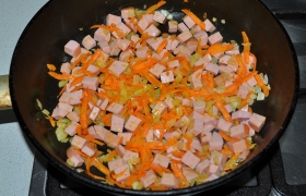 Нарезаем мелкими кубиками колбасу. Добавляем в сковороду к овощам, обжариваем 2-4 минуты.