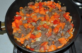 Очищенные лук и  морковь  нарезаем, добавляем в сковороду, снижаем огонь до среднего и жарим минут 10, после чего закладываем нарезанный сладкий перец.