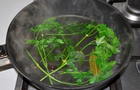 В сковороду наливаем немного кипятка, кладем стебли зелени, разделенную пополам луковицу, чуть солим.