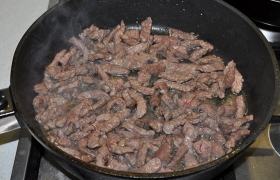 За 4-5 минут масло в толстодонной сковороде  перекаливается  на сильном огне. Кладем половину мяса и, перемешивая, обжариваем 2-3 минуты, за которые мясо прожаривается практически до готовности. Убираем на тарелку и обжариваем остаток.