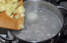 Когда брикет растаял и бульон закипел – кладем картофель. А еще - целую луковицу, ведь этот суп мы готовим без  заправки  из пассерованных овощей.