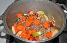 На лук кладем обжаренное мясо, рассыпаем сверху кружочки моркови, нарезанные ломтиками яблоки. Бросаем лавровый лист и веточку розмарина или тимьяна.