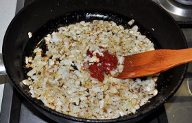 Спустя 10-12 минут добавляем к луку томатную пасту, сахар, Прованские травы, измельченный чеснок, перец и соль, перемешиваем. Отставляем сковороду, перекладываем в миску.