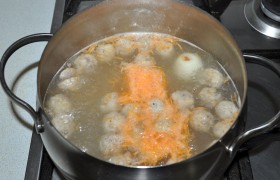 В кипящую воду кладем бульонный кубик, целую небольшую луковицу, тертую морковку и фрикадельки. Бросаем лавровый листик.
