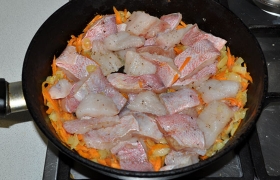 Добавляем натертую морковь, пассеруем еще 3-5 минут, кладем кусочки рыбы. 
