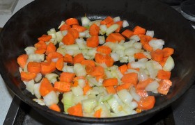 Толстодонную просторную сковороду ставим на большую конфорку с сильным огнем, наливаем 2 ст. ложки масла, даем ему 3-5 минут для  перекаливания . Засыпаем морковь и лук, перемешиваем почти без перерывов, обжариваем 3,5-4 минуты – и перекладываем в казан. 