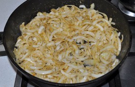 Беремся за лук. Все очищенные луковицы нарезаем полукольцами и на среднем огне  пассеруем  10-12 минут, пока лук станет мягким, зазолотится. Убираем лук в тарелку.