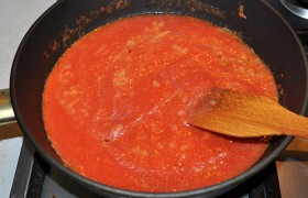 Заливаем лук в сковороде, посыпаем базиликом, орегано, сахаром, солью, измельченным чесноком, по вкусу – перцем, потушим соус 2-3 минуты.