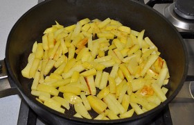 Если надо, добавляем масло и даем раскалиться на сильном огне. Закладываем картофель, нарезанный так же, как баклажан. Раскладываем брусочки, 2-2,5 минуты даем поджариться снизу.