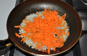 Сразу ставим воду для щей на огонь, на второй конфорке греется сковорода с маслом. В сковороду загружаем нашинкованный лук и морковь, на среднем огне овощи  пассеруются  5-7 минут, мы только иногда помешиваем.