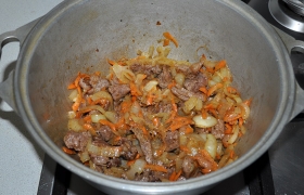 Перегружаем овощи в посуду для тушения, добавляем говядину, приправляем перцем и солью.