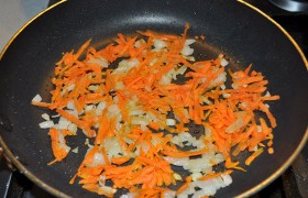 Тем временем разогреваем на среднем огне сковороду, мелко шинкуем лук, добавляем тертую морковку,  пассеруем  7-9 минут, периодически перемешивая лопаткой. 