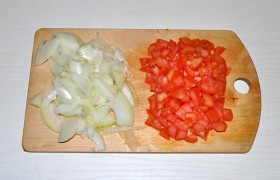 Луковицу делим на четвертинки и шинкуем, а помидор превращаем в груду мелких кубиков.