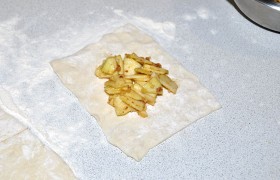 Размороженные листы теста раскатываем так, чтобы из каждого получилось по 6 квадратов. На каждый квадратик выкладываем порцию начинки.