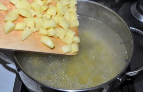Куриное мясо вынимаем, а в суп закладываем картофельные мелкие кубики. Бросаем горошки перца, лавровый лист, солим.