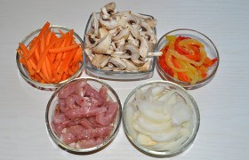 Свинину моем под струей воды, промокаем разовыми полотенцами, нарезаем поперек волокон тонкими ломтями, делим их на тонкие брусочки. Очищенные, промытые и обсушенные овощи шинкуем: лук – полукольцами, соломкой – перцы и морковь, на 2-4-6 частей режем шампиньоны (в зависимости от размера).