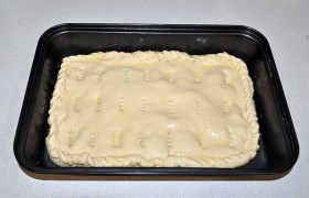 Раскатываем остаток теста и накрываем им пирог. Край заделываем приемом «веревочка» или другим. Кулинарной кистью смазываем маслом верх пирога и вилкой наносим проколы.