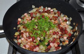 А мясопродукты в сковороде уже готовы, лук прозрачен, пахнет вкусно, и мы посыпаем соус зеленью. Готовые вареники посыпаем мясопродуктами и поливаем маслом из сковороды.