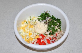 В миске соединяем рыбу и палочки, мелко порубленные лук и зелень. Готовые яйца превращаем в кубики, оставив 1-1,5 желтка для посыпки верха салата. Кладем майонез, перемешиваем. 