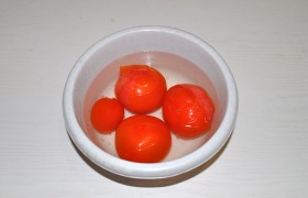 Между делом на пару минут заливаем кипятком надрезанные у плодоножки помидоры, с которых быстро начинает слезать кожица. Опускаем в холодную воду, снимаем кожицу. 
