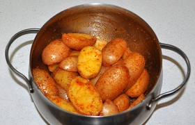 Картофель в кастрюле посыпаем специями и поливаем маслом, перемешиваем. 