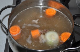 Промытое мясо кладем в холодную воду (1,5-1,8 л) и  варим  на слабом огне в закрытой кастрюле до мягкости, Вместе с луком, морковью, перцем. Из опыта – хорошо добавить в бульон куски телячьего хвоста, это сделает вкус более насыщенным. Готовое мясо вынуть, снять с костей, нарезать. И процедить бульон. 
