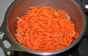 Сверху – слой тонких брусочков моркови, ее мы можем нарезать и тоненькими пластинками по длине. Не перемешивая, оставляем латку с крышкой на слабом огне, на котором мясо тушится в соках овощей 20 минут.
