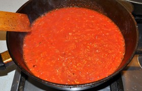 Добавляем помидоры к луку, приправляем сахаром, солью, травами, перцем, добавляем чеснок. На слабом огне выпариваем до густоты, от 20 до 40 минут.