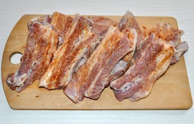 Свиные ребрышки промываем, обсушиваем, не жалея бумажных полотенец. Разрезаем мясо между ребрами и натираем их приправой для мяса и растительным маслом.