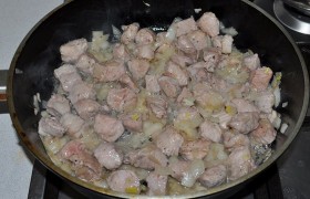 Перекаливаем  в большой толстодонной сковороде 2-3 ст. ложки растительного масла, засыпаем свинину и лук, жарим на самом сильном огне примерно 3 минуты, постоянно помешивая-переворачивая. 