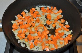 На хорошо разогретую толстостенную сковороду с растительным маслом выкладываем лук, и на огне около среднего пассеруем (обжариваем) его, помешивая, минут 5-7. Добавляем морковь и немного огня, жарим еще 3-4 минуты.