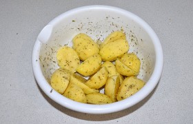 Картофель чистим, промываем и обсушиваем. Мелкие картофелины оставляем целиком, покрупнее – делим на половинки или четвертинки вдоль. Кладем в миску, перемешиваем.