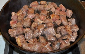  Перекалив  в толстодонной сковороде 2-3 ст. ложки масла (и не меняя самого сильного огня), обжариваем 3-4 минуты кусочки мяса до корочки, все время лопаткой переворачивая и помешивая. 