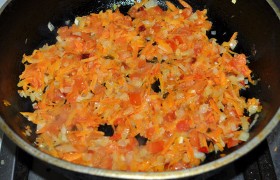 Ставим на средний огонь сковороду, разогреваем 2-3 ст. ложки масла и нашинкованный лук с морковью томим, порой помешивая, 9-10 минут, после чего добавляем измельченный помидор, оставляем томиться еще минут 10. Доливаем пару половников бульона, выключаем после закипания.