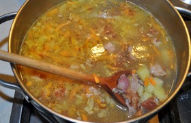 Когда картошка почти готова – 8-9 минут варки – в кастрюлю добавляем со сковороды заправку супа, а также кусочки курицы, лавровый лист, заправляем солью и перцем. Продолжаем варку в закрытой кастрюле 4-5 минут. Бросаем зелень и даем супу настояться 10-12 минут.