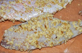 Пока в сковороде разогревается масло, панируем рыбку. Каждое филе опускаем в яйца, затем обваливаем в орехах.