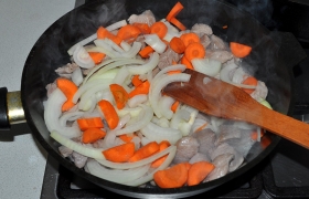 Кладем нашинкованный полукольцами лук и нарезанную морковь. Так же, не снижая огня и постоянно помешивая, обжариваем все вместе еще 4-5 минут.