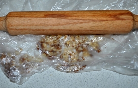 Измельчаем ядра орехов простым способом: скалкой в пакете.