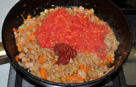 Тертые помидоры и томатную пасту добавляем в сковороду с тушенкой, тушим 2-3 минуты, приправляем солью, перцем, сахаром.