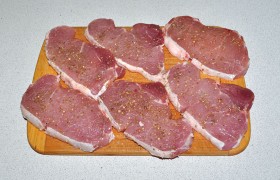 Лишнее сало срезаем, на оставленном слое делаем надсечку (видно на фото). Посыпаем ломти мяса с обеих сторон перцем, солью, орегано, похлопаем ладонью, чтобы приправы хорошо прилипли к поверхности мяса.