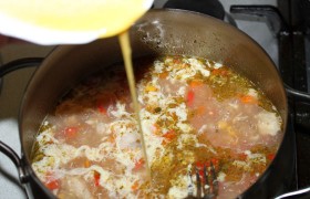 Спустя  4-5 минут начинаем вливать тоненькой струей взбитые яйца, а в правой руке держим вилку и быстро перемешиваем, разделяя струйку в супе, чтобы яйца не сварились неаппетитным комком.